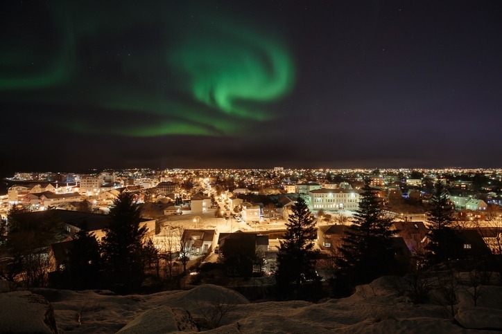 Panorama von Reykjavik bei Nacht mit Nordlichtern