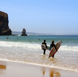 Zwei Surfer gehen mit Surfbrettern auf das Meer zu